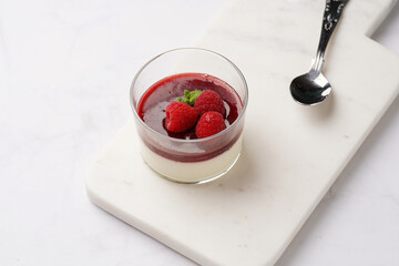 Italian dairy dessert panna cotta with raspberry jam, fresh raspberries and mint on marble board