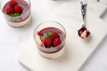 Italian dairy dessert panna cotta with raspberry jam, fresh raspberries and mint on marble board