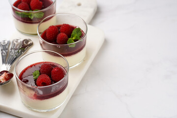 Italian dairy dessert panna cotta with raspberry jam, fresh raspberries and mint on marble board, copy space