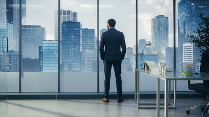 Confident Young Businessman in a Perfect Tailored Suit Standing in His Modern Office Looking out of...