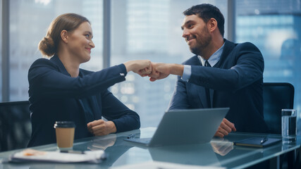 Corporate CEO and Investment Manager Talking, Using Laptop Computer while Sitting in Meeting Room in Office. Two Successful Businesspeople Fist Bump Over a Prospective Fintech Investment Deal.