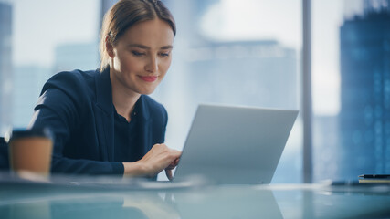 Close Up Portrait of a Successful Businesswoman Working on Laptop in Open Office with Colleague,...