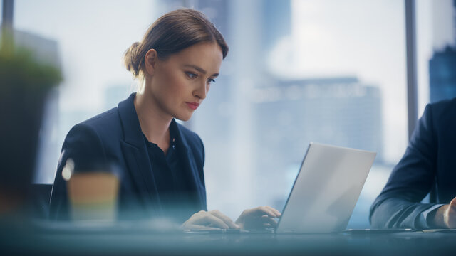 Close Up Portrait of a Successful Businesswoman Working on Laptop in Open Office with Colleague, Confident Female CEO Analyze Financial Projects. Manager at Work Planning Marketing Campaign.
