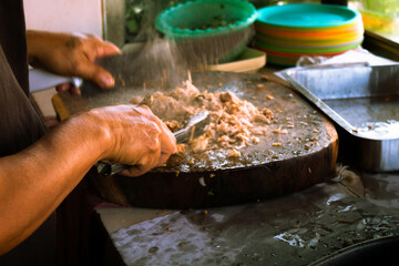 Close up from the hands of a Mexican man grinding meat for traditional mexican tacos