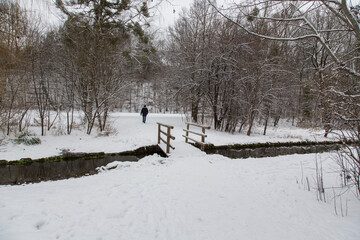 A wooden bridge over the Brunnbach stream in an idyllic winter snow scenic landscape with trees...