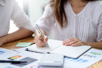Close-up of businesswoman holding a pen working by taking note at office.