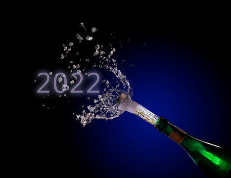 champagne bottle explosion with cork popping splash and New Year date 2022 against a dark background with blue to black gradient, copy space