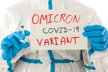 Medical nurse in PPE and latex gloves holding a sign that reads: 'OMICRON VARIANT COVID-19' and in...
