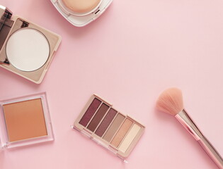 Make up layout,eye shadow, brush, and face powder on pastel pink background. Minimal and luxury make up, cosmetic or beauty salon composition. Flat lay, top view, copy space.