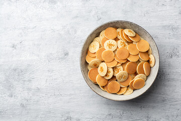 Pancake cereal or mini pancakes in bowl on concrete background