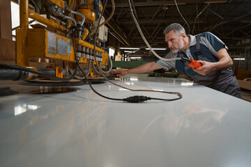 Low angle photo of serious joiner looking at gadget