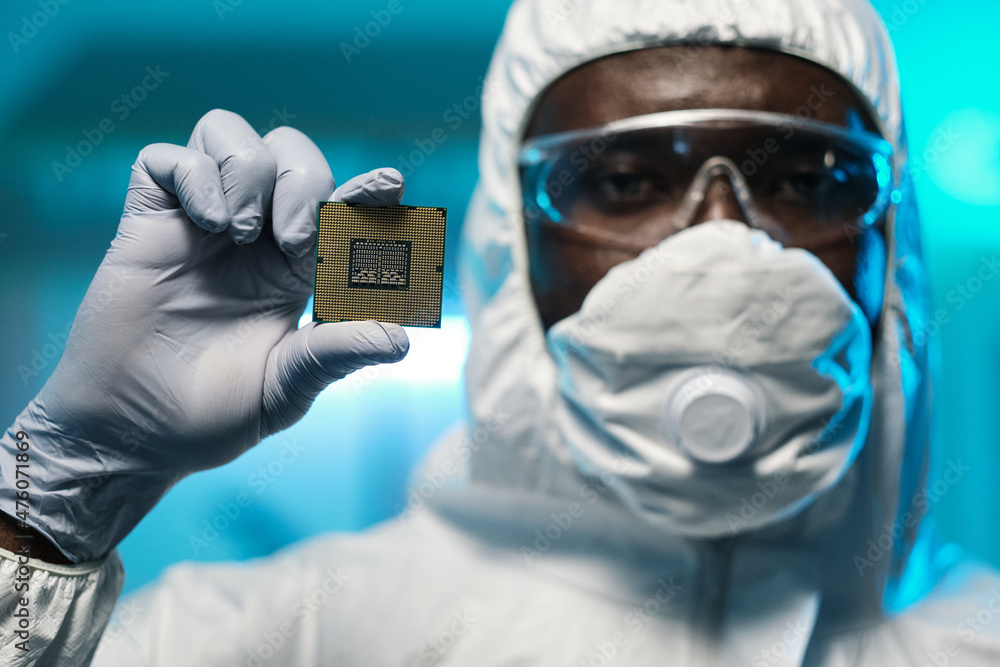 Poster Gloved hand of young African scientist holding microchip while standing in front of camera and looking at you