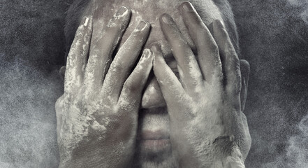 Man with hands on his face covered by the dust