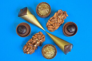 Top view of various chocolate pralines on pastel background. Top view of variety chocolate pralines. Flat lay. Mixed luxury dark and milk chocolate truffles. Assorted delicious handmade chocolate