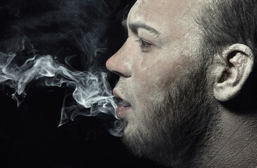 Dirty man smoking on a black background