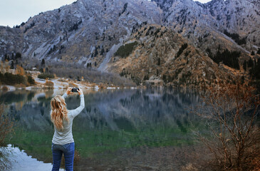 Fototapeta na wymiar Woman making mobile photo at the mountain lake