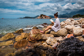 woman reads the book near Sveti Stefan