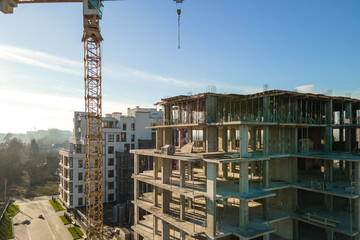Aerial view of high tower crane and residential apartment buildings under construction. Real estate development.