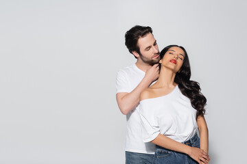 Fototapeta premium young man touching neck of passionate woman with closed eyes isolated on grey.