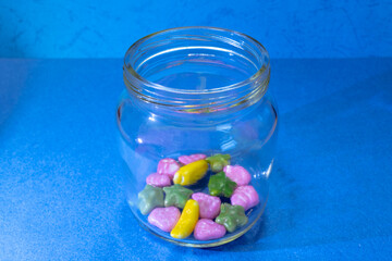 Small glass jar with colored sweets. An open jar of sweets