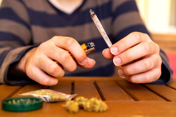 Fototapeta na wymiar Front view of young person smoking cannabis joint on a table full of weed.