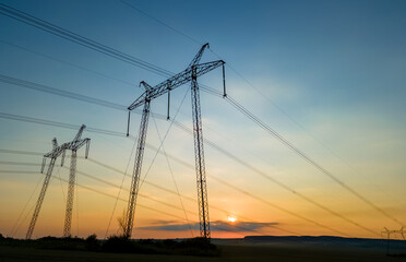 High voltage towers with electric power lines at sunset