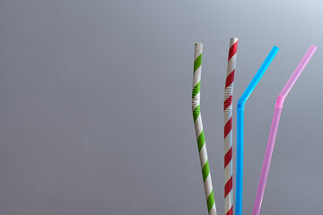 View of a pair of paper straws and a pair of plastic straws. Environmental concept.
