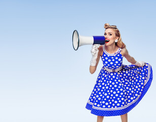 Portrait of woman holding megaphone loudspeaker, dressed in pinup style dress in polka dot and...