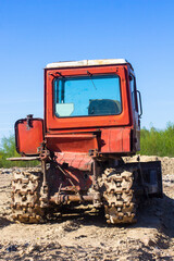 Fototapeta premium Old red bulldozer against the blue sky. Back view.