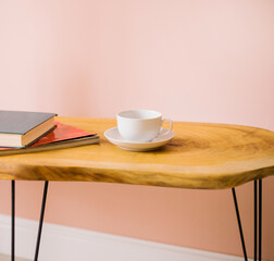 Wooden coffee table. There is a cup and saucer on the table and books. Modern interior.