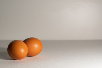 Two textured, chicken eggs, on a light background, on a light substrate. Chicken eggs, two pieces, with a textured surface.