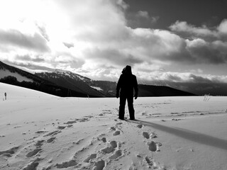 black and white photo of man from behind looking at the horizon on the snowy mountain