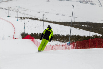 snowboarder is jumping with snowboard from snowhill. Skier skiing downhill in high mountains....