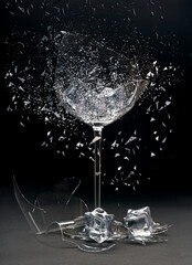 Exploding wine glass that breaks on a black background. Icecubes on bottom