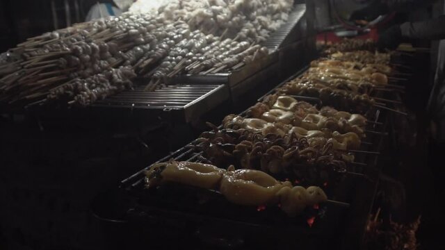 Grilled squids preparing for customer. Fresh squid in stick grill on street food.
