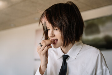 woman with short hair putting food in her mouth with her hand