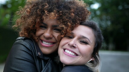 Fototapeta premium Diverse friendship, two young women embrace cheek to cheek, diversity concept