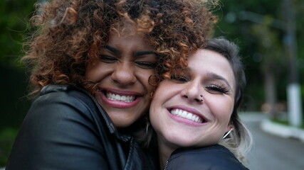 Obraz premium Diverse friendship, two young women embrace cheek to cheek, diversity concept