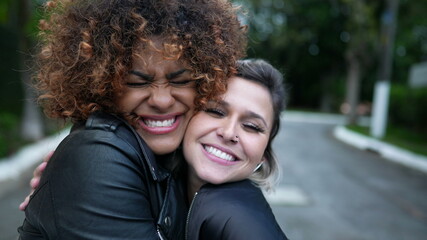 Diverse friendship, two young women embrace cheek to cheek, diversity concept