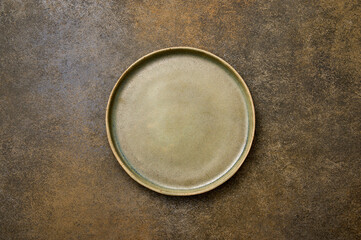 Top view empty green ceramic plate on brown rustic background, copy space