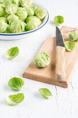 removing outer leaves of fresh and ripe Brussel sprouts on wooden cutting board