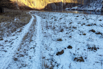 country road in the snow dry blades of grass stick out from the snow