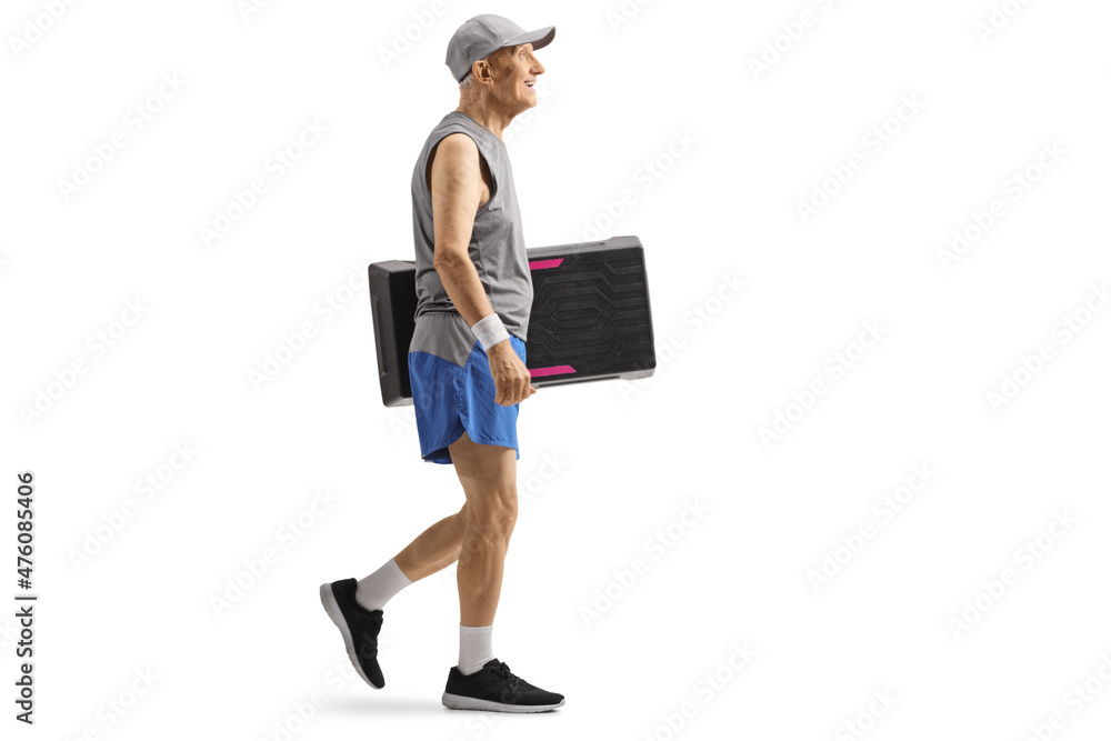 Wall mural full length profile shot of an elderly man in sportswear walking and carrying a step aerobic platfor