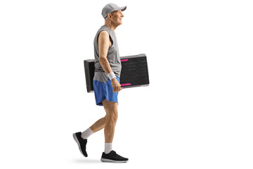 Full length profile shot of an elderly man in sportswear walking and carrying a step aerobic...