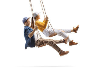 Profile shot of male and female teens swinging on wooden swings