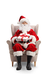 Full length portrait of santa claus sitting in an armchair with a present in his hands