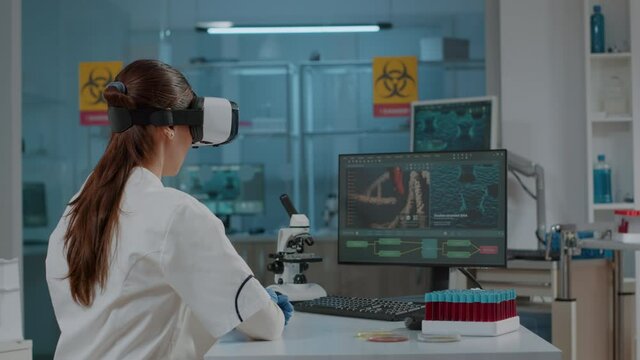Microbiology specialist using vr glasses in laboratory to work on science experiment for development. Scientist working with virtual reality headset in research lab for futuristic presentation