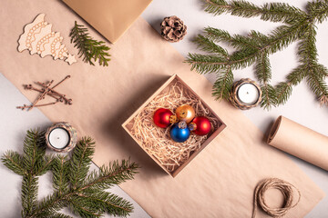 Packing a gift for Christmas and new year in eco-friendly materials: kraft paper, live fir branches, cone, twine. Tags with mock up, natural decor, hand made, flatlay.