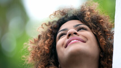 Black hispanic woman closing eyes in contemplation. African Brazilian girl opening eye to sky