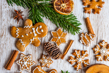 Christmas gingerbread and sweets are placed on wooden desk. Cookies and sweet food in shape of stars and snow flakes. Winter theme, rustic style. Pine trees on the side. Candy stick and other spice.